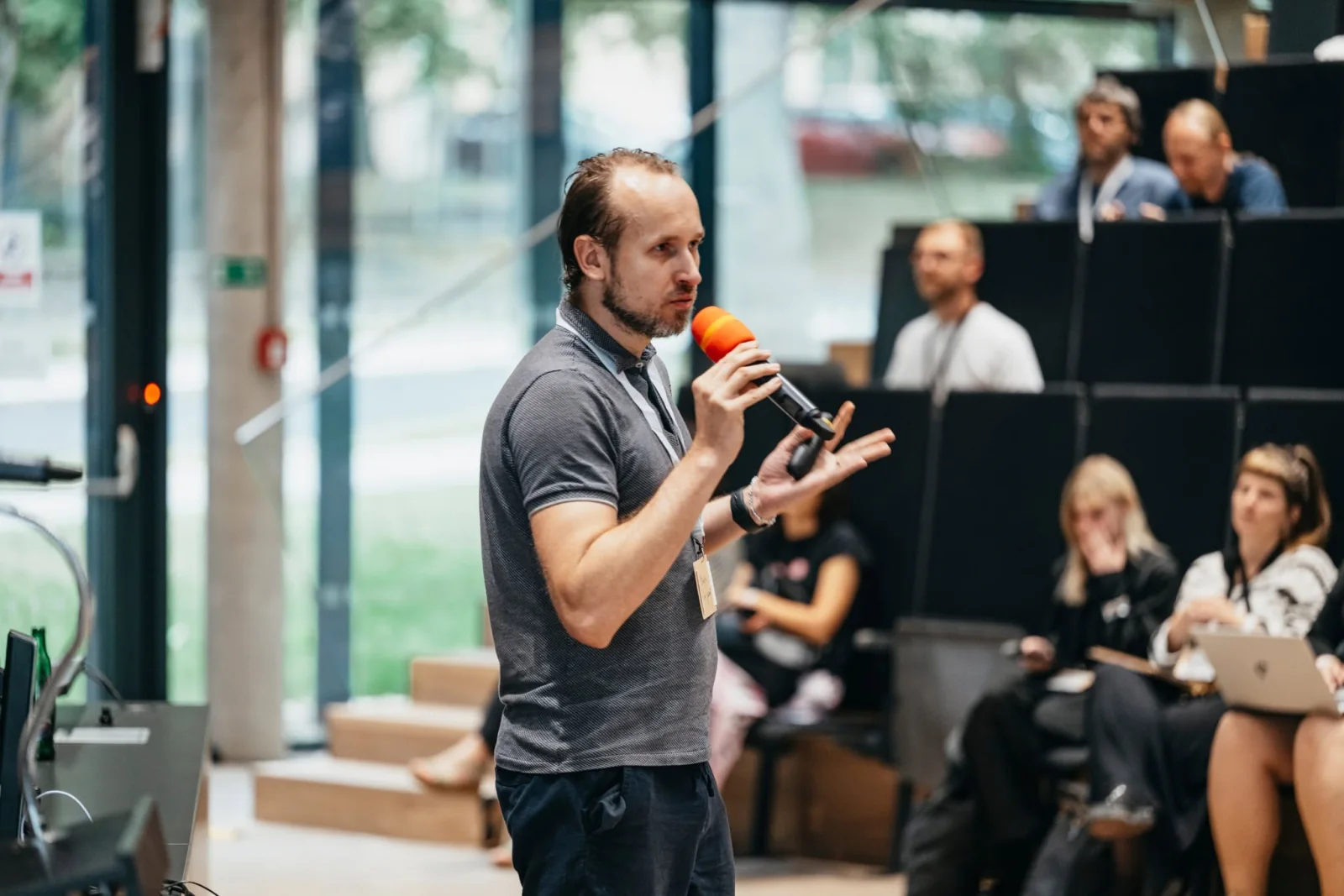 Jakub Roh speaking into a microphone at a conference in front of an audience